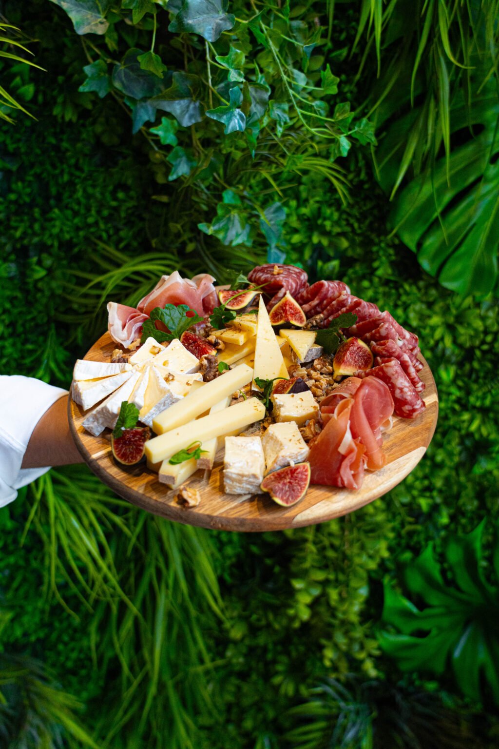 A cheese and charcuterie platter on a bed of greenery